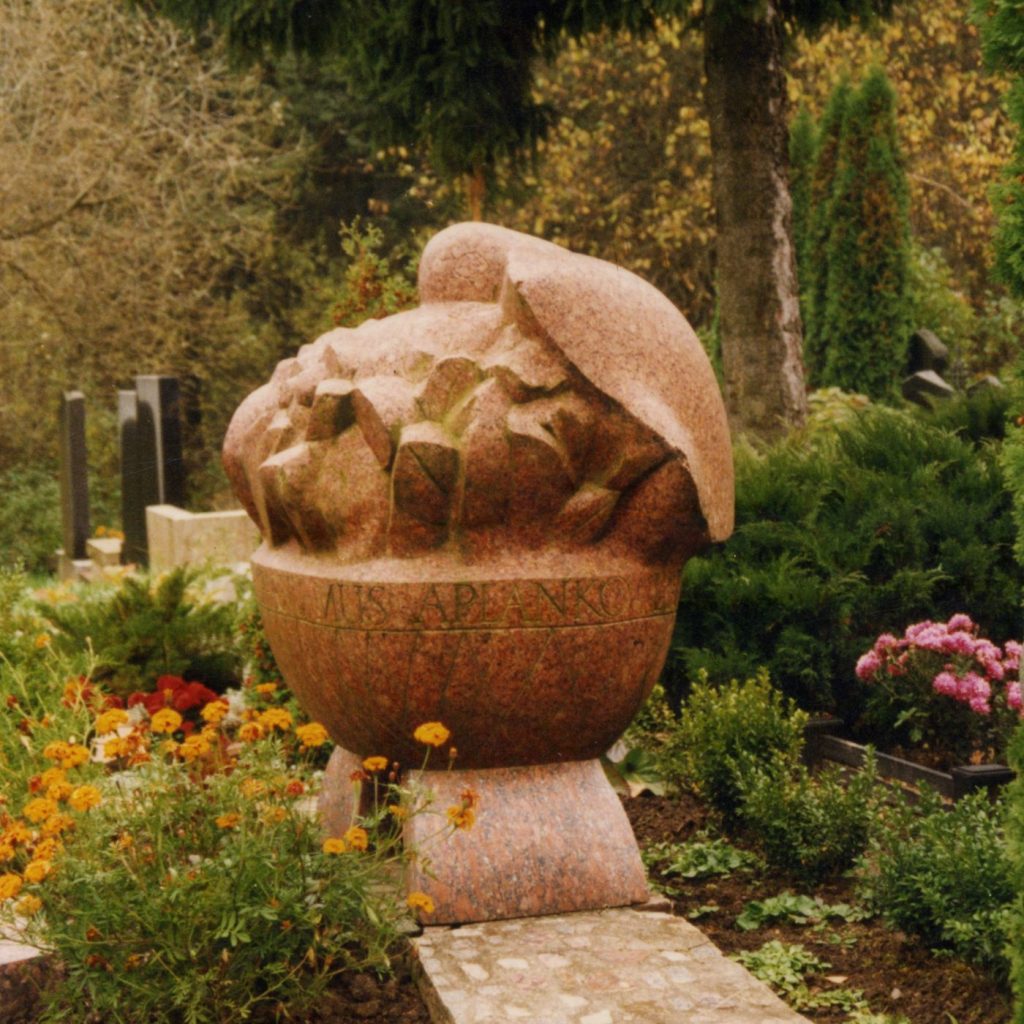 Puidokų šeimos kapavietė. Paukštis apglėbęs krepšį, ant kurio užrašyta „Ant džiaugsmo sparnų aplanko liūdesys“. Šlifuotas granitas. 1982 m. Romainių kapinės, Kaunas