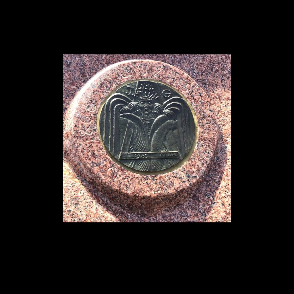 Teresės Garšvaitės-Buzienės antkapis. Šlifuotas granitas, H – 0,80. Bronza medalis, Angelas, diametras 1,28 m. 1985 m. Jodaičių kapinės, Raseinių raj.
